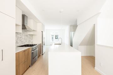 Victoria apartment for rent - A modern kitchen with wooden cabinets and a white countertop.