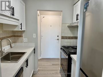St. Catharines (Carlton/Bunting) condo for rent - A kitchen with white cabinets and a white door in the background.