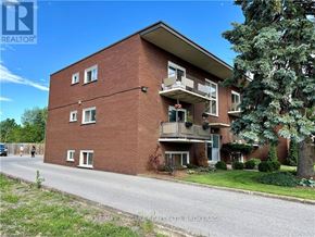 St. Catharines (Carlton/Bunting) condo for rent - A red brick apartment building with a balcony on the second floor.