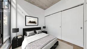 Toronto (South Riverdale) condo for rent - A bedroom with a bed, nightstand, and a framed picture on the wall.