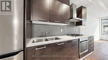 Toronto (South Riverdale) condo for rent - A modern kitchen with stainless steel appliances and wooden cabinets.