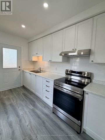 Halton Hills (Ac Acton) apartment for rent - A modern kitchen with white cabinets and a stainless steel stove.