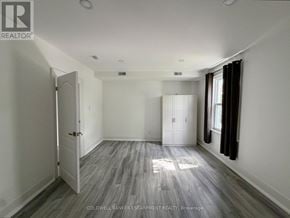 Halton Hills (Ac Acton) apartment for rent - A room with a wooden floor and white walls, with a door on the left and a window on the right.