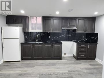 Brampton (Madoc) apartment for rent - A kitchen with black marble countertops and dark wood cabinets.