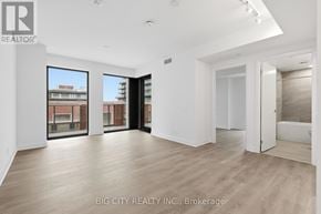 Toronto (Thorncliffe Park) condo for rent - A spacious room with wooden flooring and large windows overlooking a cityscape.