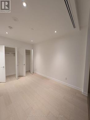 Toronto (Annex) condo for rent - A spacious room with white walls and wooden flooring.