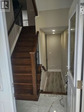 Toronto (Kennedy Park) apartment for rent - A hallway with a staircase and a door leading to another room.