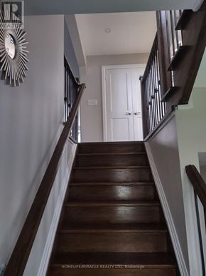 Toronto (Kennedy Park) apartment for rent - A staircase with a wooden floor and a white door at the top.