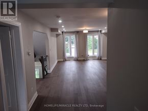 Toronto (Kennedy Park) apartment for rent - A spacious room with wooden flooring and a sliding glass door leading to a garden.