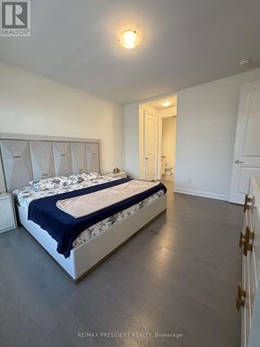Vaughan (Vellore Village) apartment for rent - A bedroom with a bed, wooden floors, and a white door.