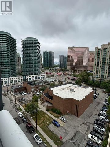 Toronto (Willowdale East) condo for rent - A parking lot with cars and a building with a white roof.