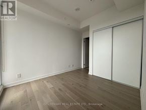 Toronto (Willowdale East) condo for rent - A room with white walls and wooden flooring, with a sliding door on the right.