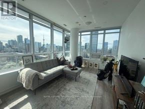 Toronto (Church-Yonge Corridor) condo for rent - A living room with a large window overlooking a city skyline.