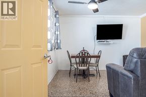 Erieau apartment for rent - A living room with a grey couch, a wooden table with four chairs, a flat screen TV, and a ceiling fan.