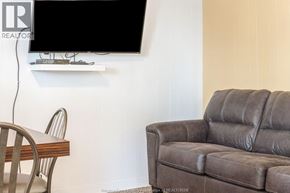 Erieau apartment for rent - A living room with a brown leather couch and a flat screen TV mounted on the wall.