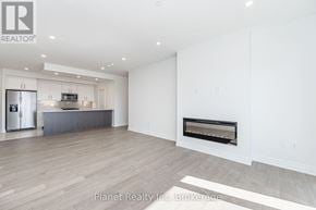 Guelph (Pineridge/Westminster Woods) condo for rent - A spacious living room with a fireplace and a kitchen area in the background.