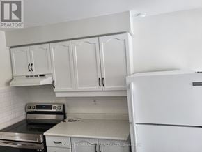 Barrie (Innis-Shore) apartment for rent - A white kitchen with a refrigerator, stove, and cabinets.