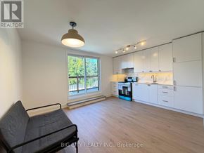 Toronto (Rockcliffe-Smythe) apartment for rent - A living room with a black chair and a window with a view of trees.
