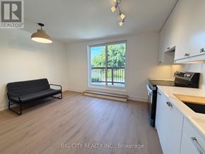 Toronto (Rockcliffe-Smythe) apartment for rent - A living room with a black sofa and a window overlooking a balcony.