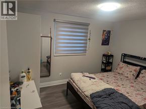 Brantford apartment for rent - A bedroom with a bed, a nightstand, and a window with blinds.