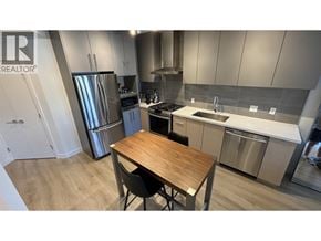 Coquitlam apartment for rent - A modern kitchen with a wooden table and stainless steel appliances.