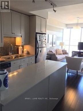 Toronto (Niagara) condo for rent - A modern kitchen with a refrigerator, sink, and a dining area with a couch and chairs.