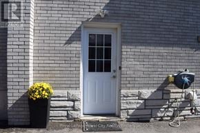 Halton Hills (Ac Acton) apartment for rent - A white door with a glass window is flanked by a planter with yellow flowers and a mailbox.