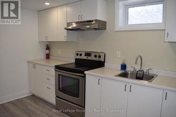 Halton Hills (Ac Acton) apartment for rent - A white kitchen with a black stove top oven and a window.