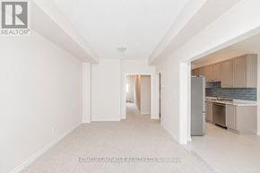 Thorold (Thorold Downtown) townhouse for rent - A spacious, empty room with a kitchen area visible through the open door.