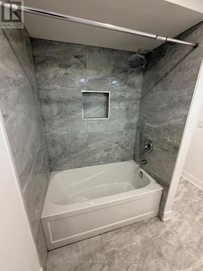 Whitby (Downtown Whitby) apartment for rent - A bathroom with a white tub and grey tiled walls.