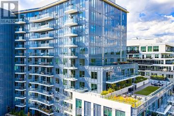 Guelph (St. Patrick's Ward) condo for rent - A modern glass building with balconies and a green roof.