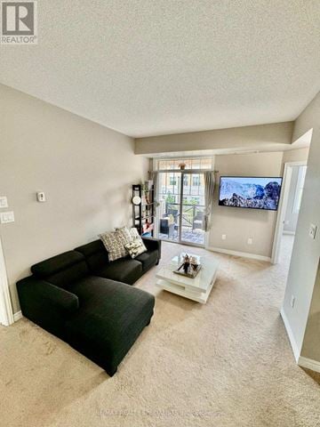 Oakville (Ro River Oaks) townhouse for rent - A living room with a black couch and a flat screen TV mounted on the wall.