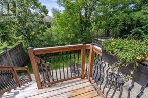 Burlington (Alton) apartment for rent - A wooden deck with a railing and a bench overlooking a lush green forest.
