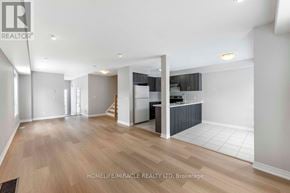 Oshawa (Windfields) townhouse for rent - A spacious living room with wooden flooring and a kitchen area in the background.