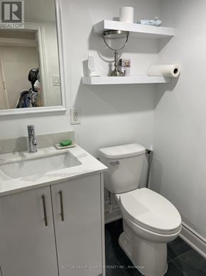 Mississauga (Port Credit) multi-family for rent - A white toilet in a small bathroom with a sink and mirror.