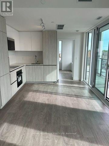 Brampton (Fletcher's Creek South) condo for rent - A modern kitchen with white cabinets and a wooden floor.