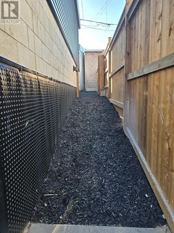 Toronto (Keelesdale-Eglinton West) apartment for rent - A narrow alley with a wooden fence on one side and a metal fence on the other.