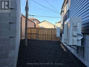 Toronto (Keelesdale-Eglinton West) apartment for rent - A backyard with a fence and a wall with a Realty sign.