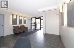 Kitchener condo for rent - A spacious hallway with a couch, chairs, and a door leading to another room.