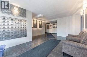 Kitchener condo for rent - A realtor office with a grey carpet and a grey couch.