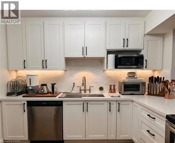 Kitchener condo for rent - A kitchen with white cabinets and a black dishwasher.