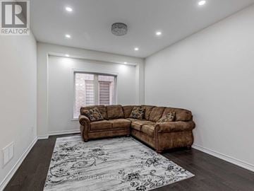 Oshawa (Taunton) apartment for rent - A living room with a brown couch and a rug that says "HOUSE OF MIRACLES".