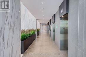 Mississauga (City Centre) condo for rent - A hallway with a marble wall on the left and a row of plants in the middle.