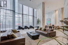 Mississauga (City Centre) condo for rent - A living room with a brown couch, a coffee table, and a large window with blinds.
