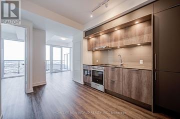 Mississauga (City Centre) condo for rent - A modern kitchen with wooden cabinets and a stainless steel oven.