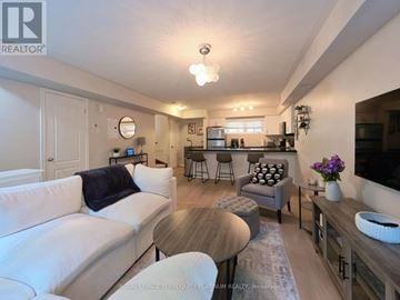 Oakville (Ro River Oaks) condo for rent - A living room with a white couch and a wooden coffee table.