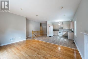 Caledon (Caledon East) apartment for rent - A spacious room with wooden flooring and a kitchen area in the background.