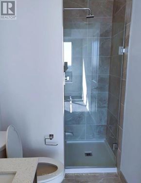 Mississauga (Fairview) condo for rent - A bathroom with a toilet, sink, and glass shower stall.
