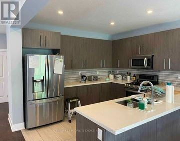 London North (North C) house for rent - A kitchen with a stainless steel refrigerator and wooden cabinets.
