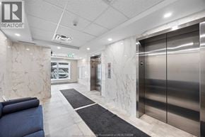 Kingsville condo for rent - A hallway with a blue couch and a silver elevator.